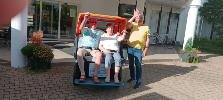 Zwei Fahrgäste und ein Fahrer vor der Rikscha